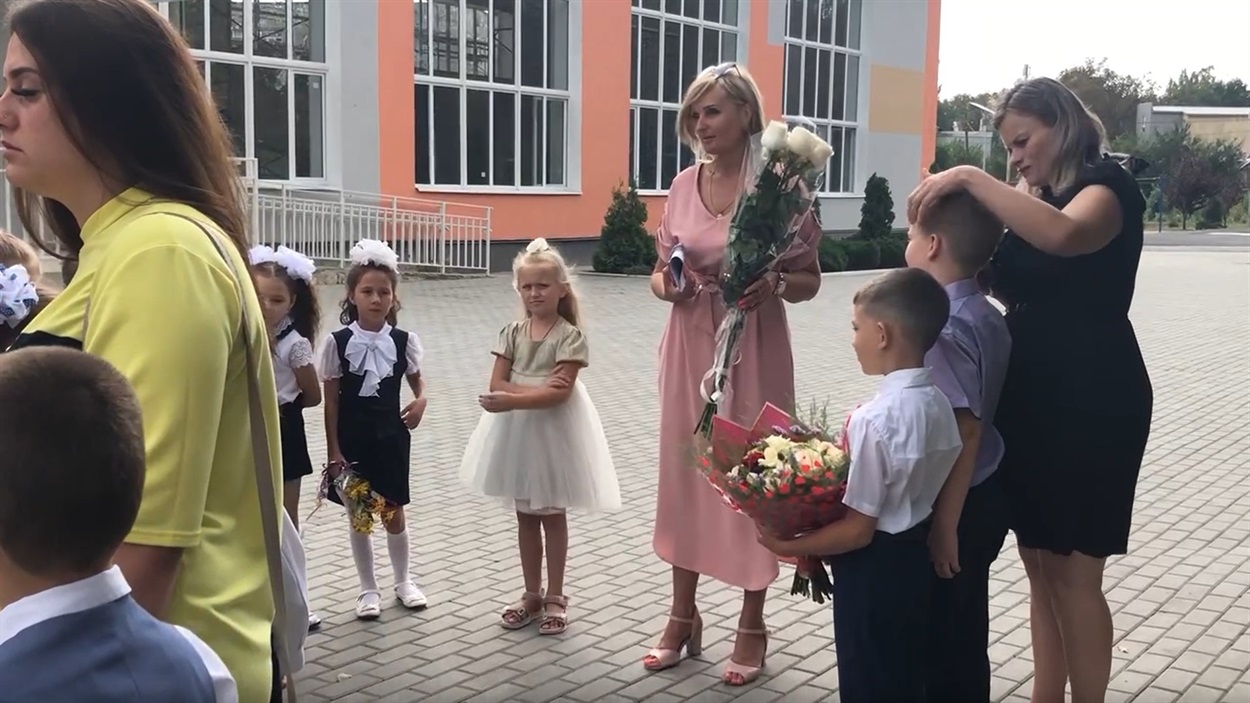 Вчителька, яка добровільно погодилася співпрацювати з окупантами, тримає букет троянд