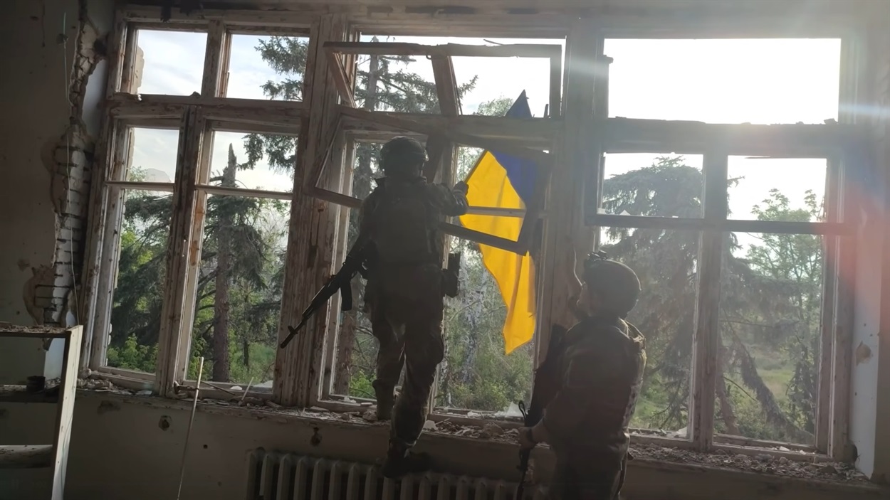 Військовий з позивним Олімп вішає український Прапор над сільським клубом у Благодатному 
