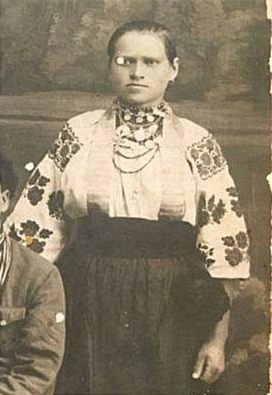 Жінка має коралове намисто, дукати, чокер та хрест