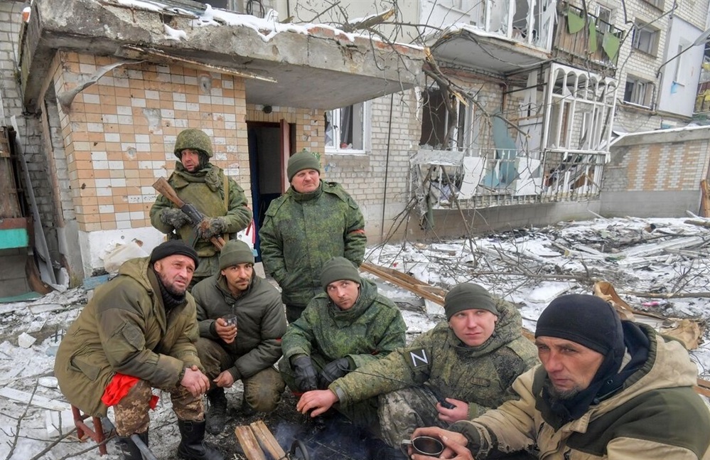Окупанти снідають на тлі зруйнованого будинку у Волновасі (березень 2022)